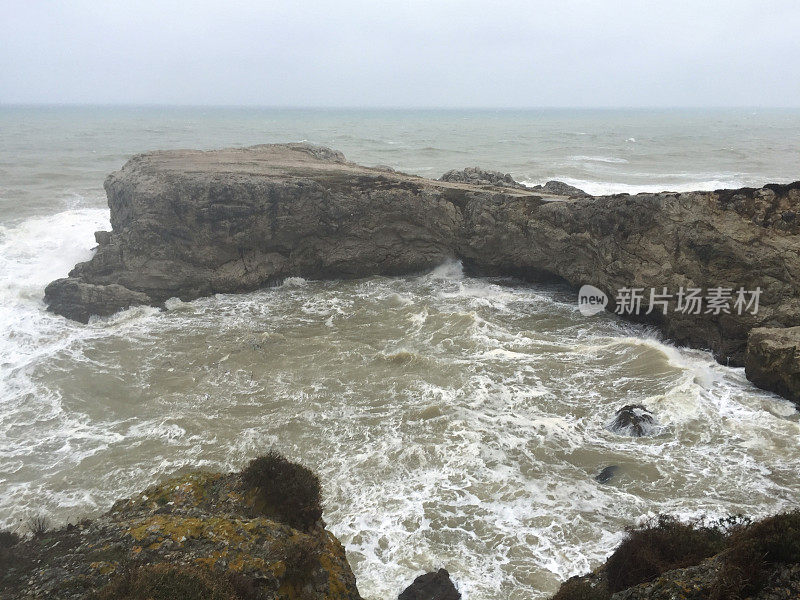 暴风雨天气中的海边悬崖。海岸线岩石，波涛汹涌的大海和多雨的天气背景