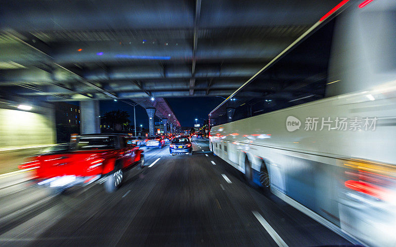 公共汽车和汽车在夜晚行驶在范威克高速公路下的立交桥上。长曝光，POV的驱动程序