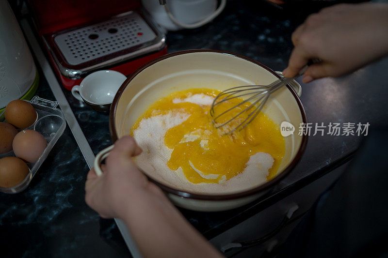 穿着灰色围裙的年轻女子打破鸡蛋