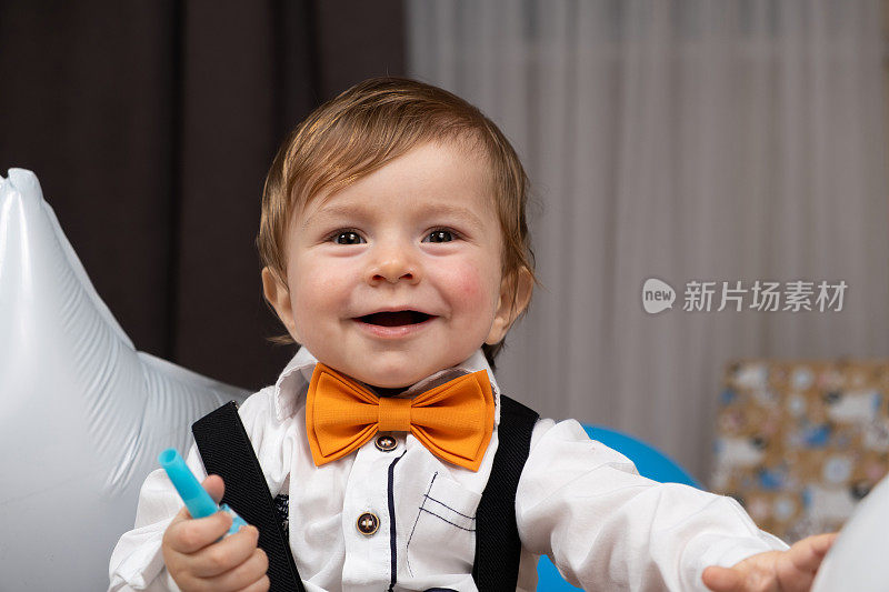 一个一岁的红发男孩的肖像，穿着衬衫，打着领结，穿着背带裤