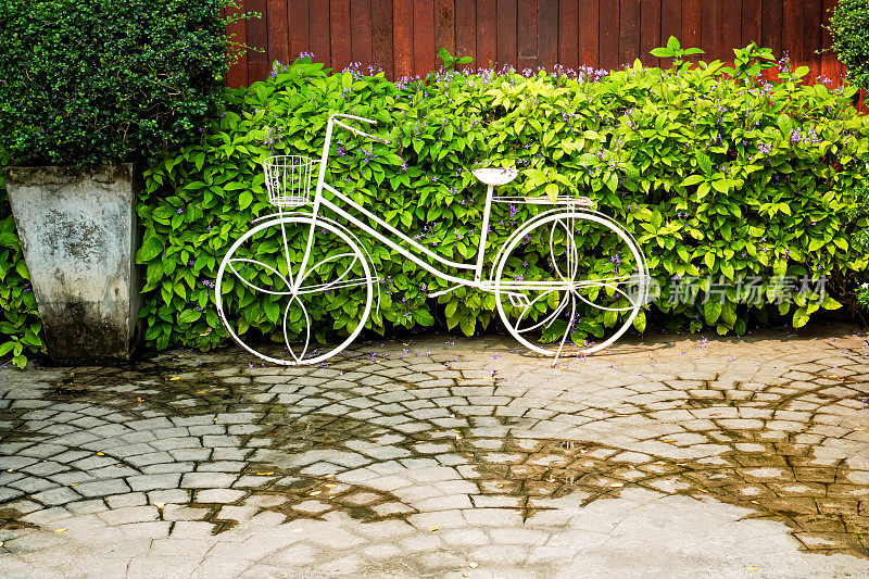 一辆未使用的白色自行车的特写照片被装饰在一个观赏性的花园中，以创造美感和风格。