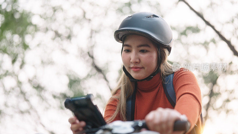 女子骑自行车旅行时使用智能手机。