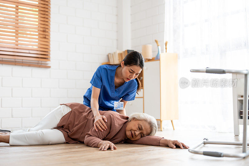 亚洲护工帮助家中摔倒的老年女性。老年患者在进行物理治疗时发生事故，然后在客厅被有吸引力的治疗师护士救出。