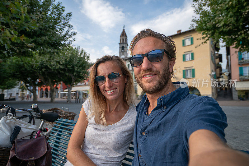 一对年轻夫妇在美丽的瑞士小镇上自拍，湖边以山为背景
