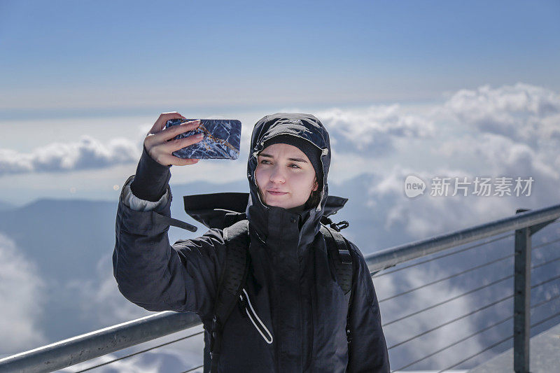 一名女子在雪地上用智能手机自拍