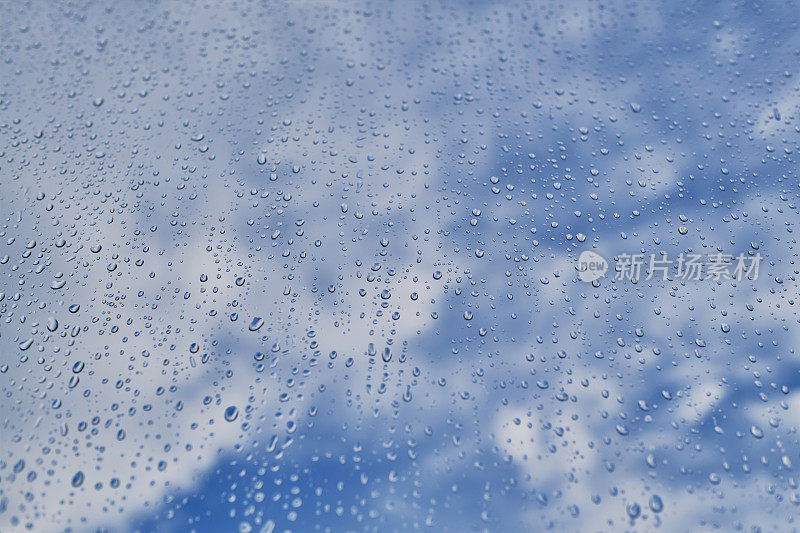 暴风雨过后，透过窗户可以看到蓝天和白云的雨滴。