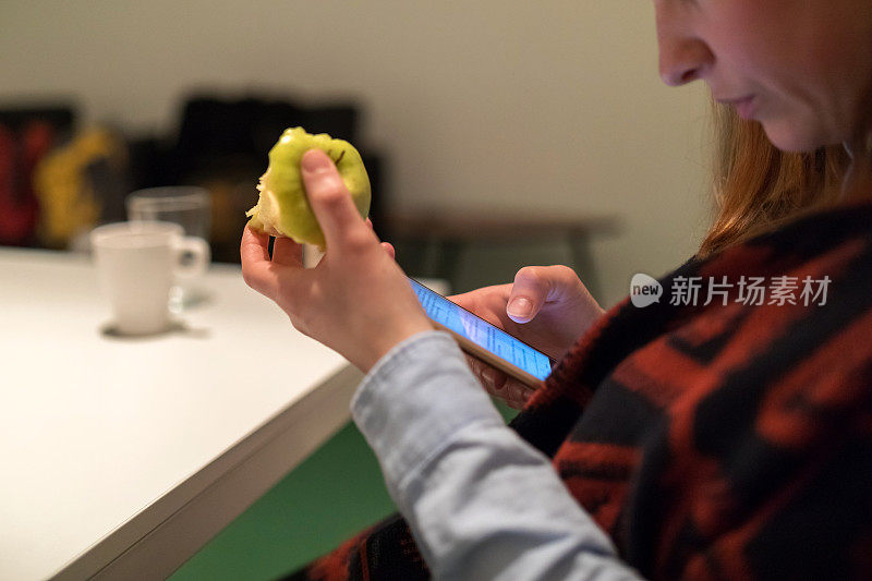 女人一边吃苹果一边用智能手机上网
