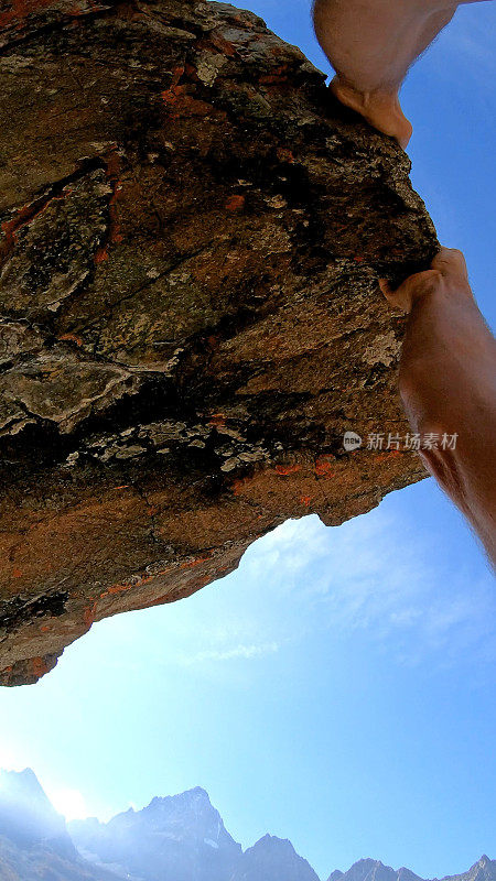 日出时，男性攀登者登上岩石顶峰