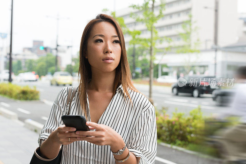 日本京都，一名千禧一代女性通过手机站在街头