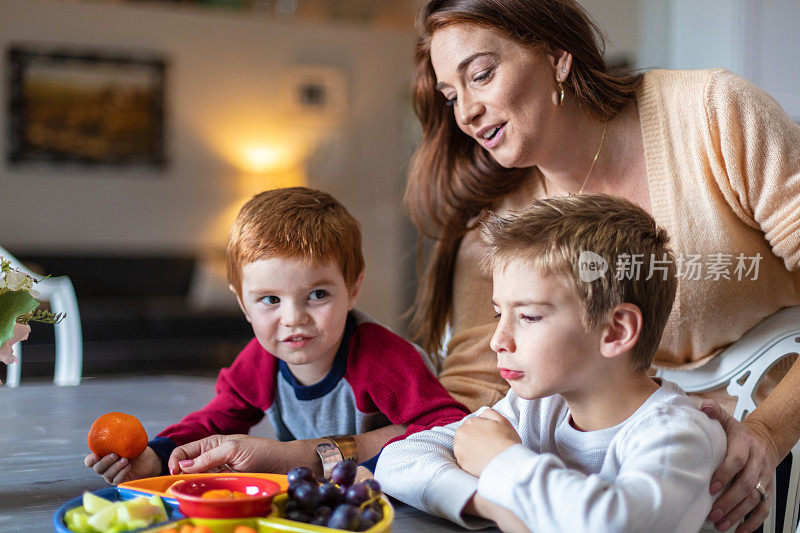 幸福的家庭红发和金发男孩与母亲活跃和满足在家