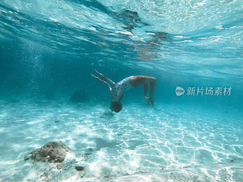 女孩在美丽的绿松石水中游泳