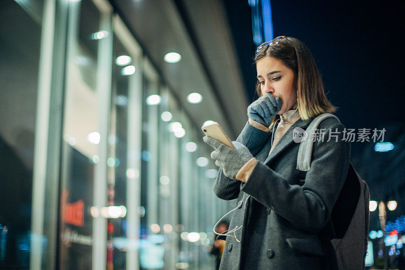 年轻漂亮的女人晚上在街上听音乐