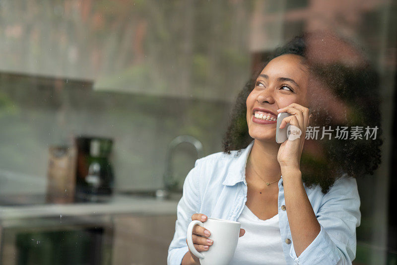 快乐的女人在家里讲着电话，笑着