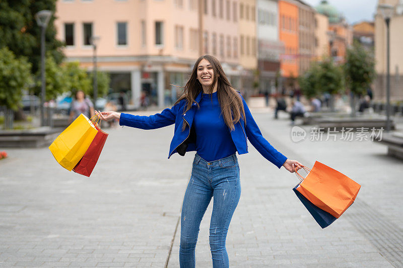 年轻快乐的女人拿着购物袋走在街上