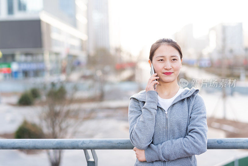 亚洲年轻女子在城市公共广场使用手机