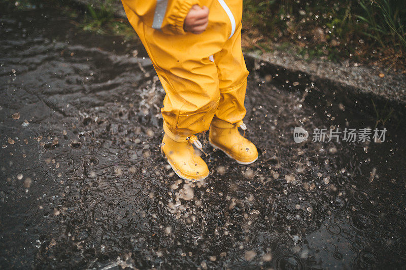 小男孩在雨中玩耍，跳进水里画画