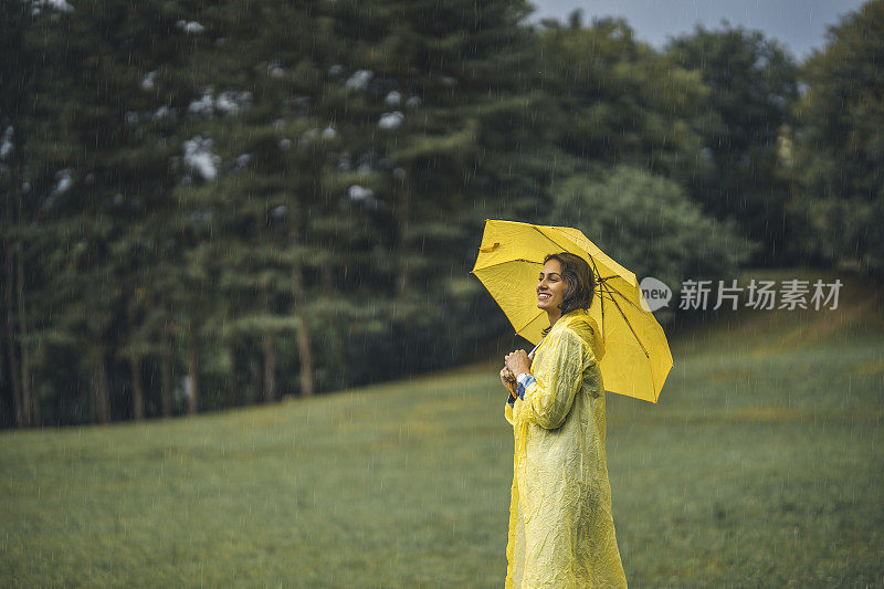 快乐的女人微笑着行走在雨天