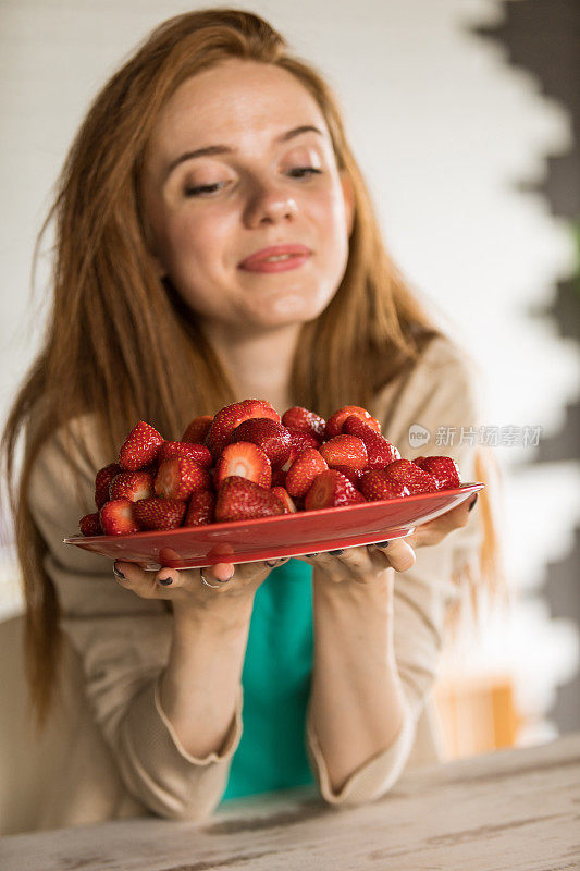 给年轻女子盛满新鲜草莓的盘子
