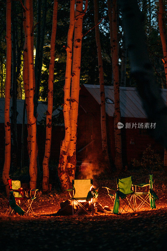 在大梅萨国家森林的梅萨湖旅游度假区的小木屋附近的黄昏，环绕着熊熊篝火的野营椅