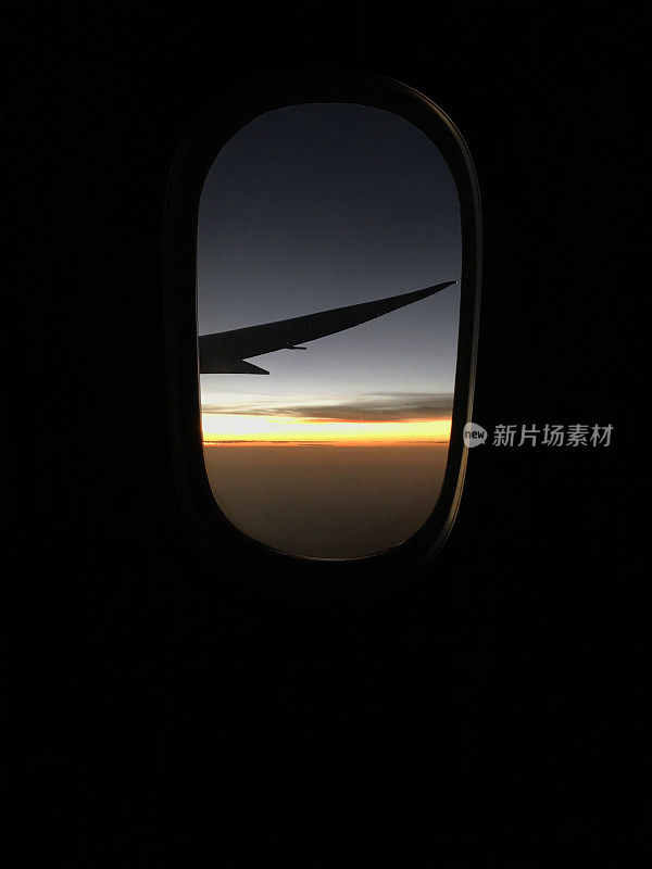 从机场起飞后从舷窗飞机经济舱鸟瞰日出天空。