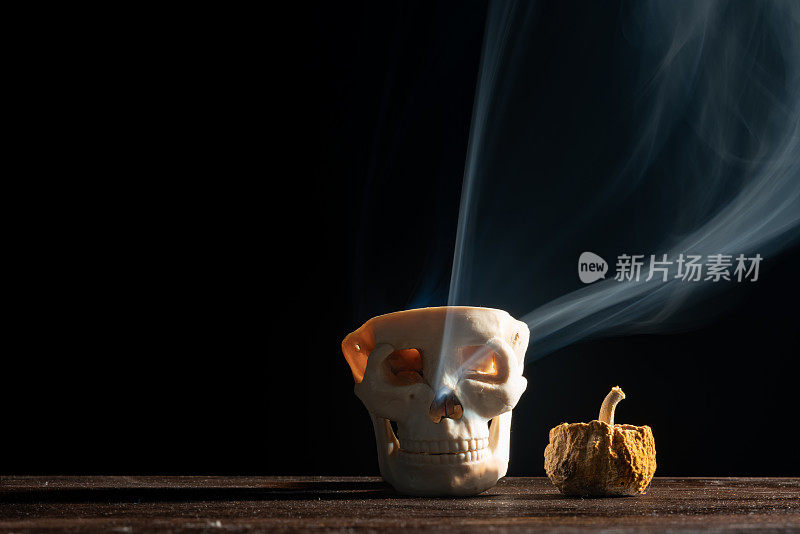 万圣节的黑色背景，南瓜，烟雾和人的头骨