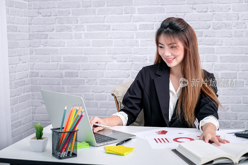 漂亮的女商人或财务经理在现代办公室里用笔记本电脑工作。