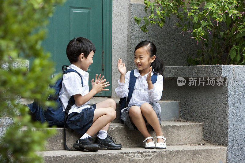 儿童坐在普通社区门口台阶上玩游戏