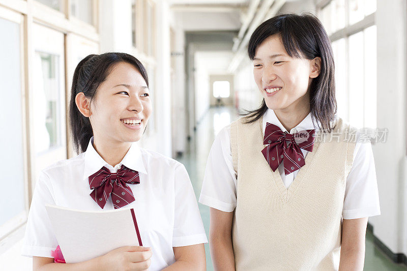 两名日本女学生微笑着走在学校走廊上