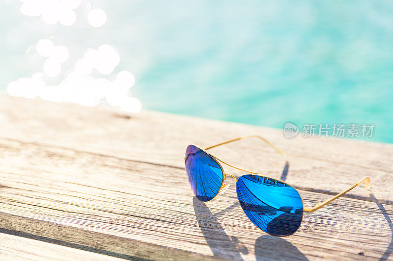 海边木制甲板上的蓝色太阳镜