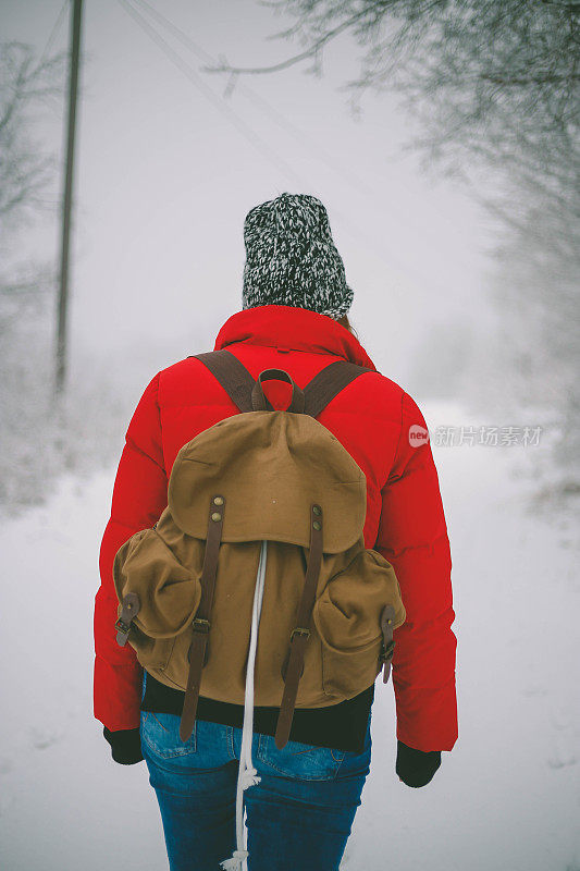 女徒步旅行者背包和雪鞋在雪地上的雪鞋