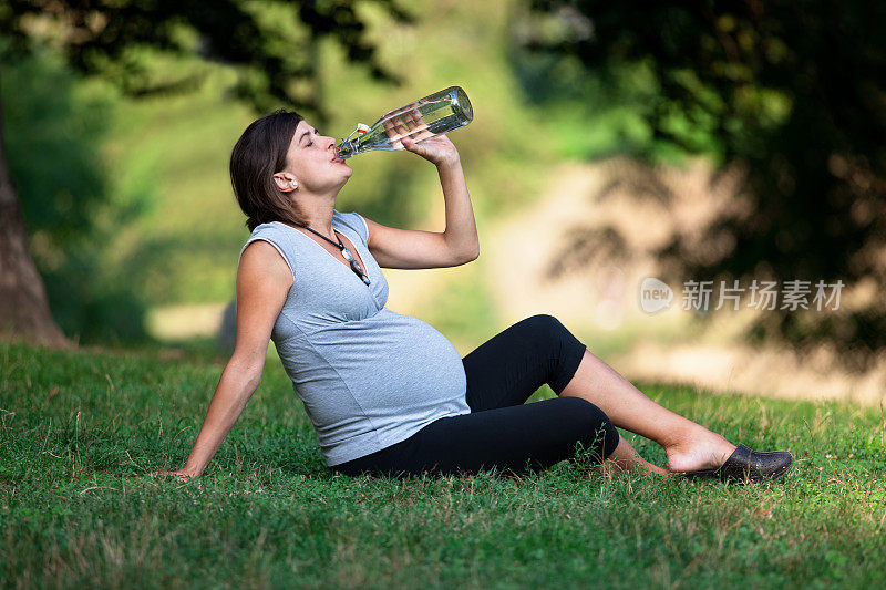孕妇在公园的草地上喝水