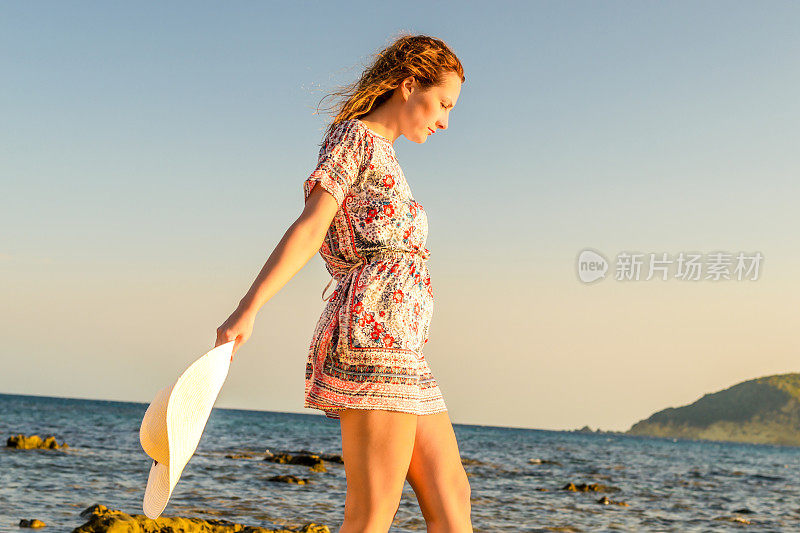 戴着帽子的女人走在海滩上