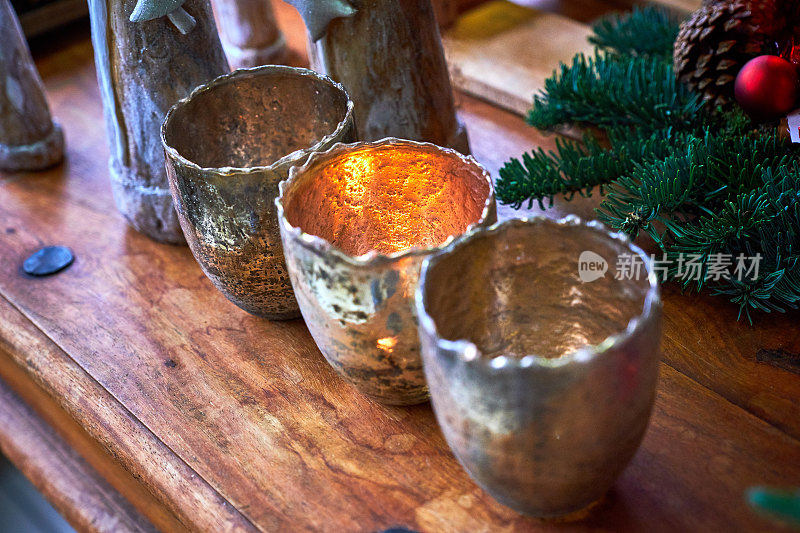 圣诞装饰，复古的样子:桌子上有三个金色的烛台，周围是烛台和木制的人物