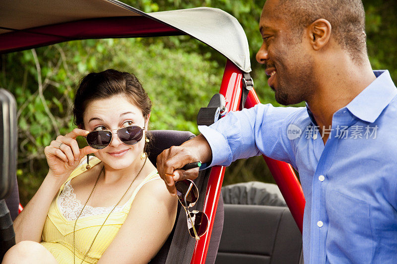 非洲裔男子在吉普车里与年轻女子交谈。
