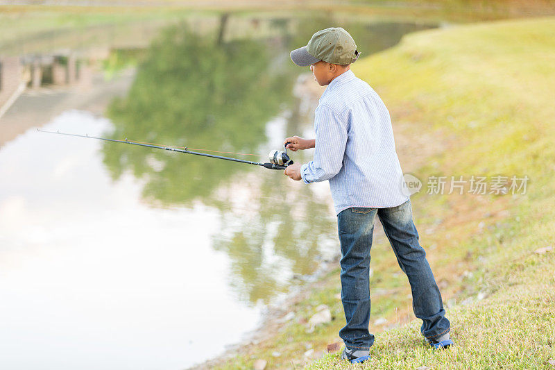 专注的非裔美国男孩在池塘里钓鱼