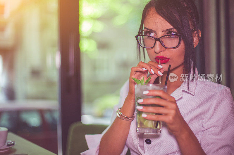 美丽的年轻女子在酒吧喝鸡尾酒莫吉托