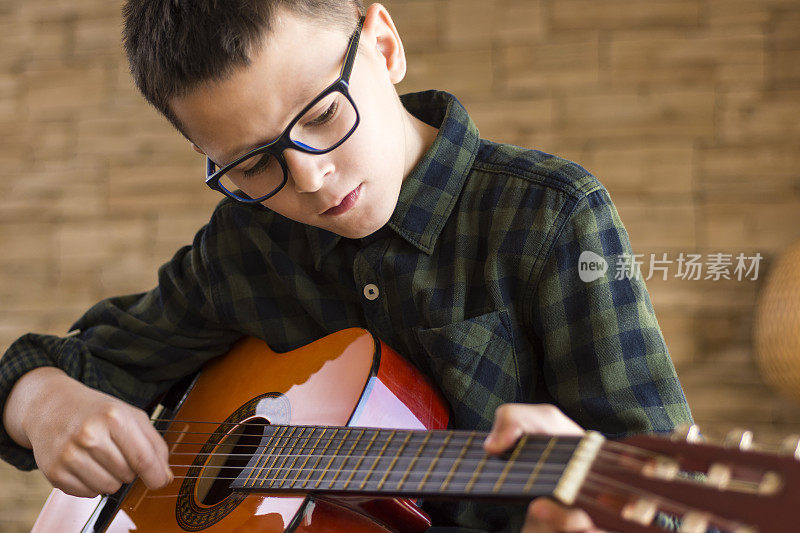 戴眼镜的男孩在客厅弹原声吉他