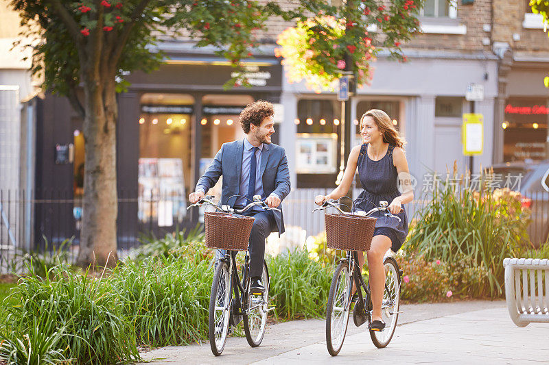 快乐的商业人士骑着自行车穿过城市公园