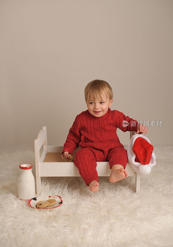 笑着的小男孩坐在木床上等圣诞老人