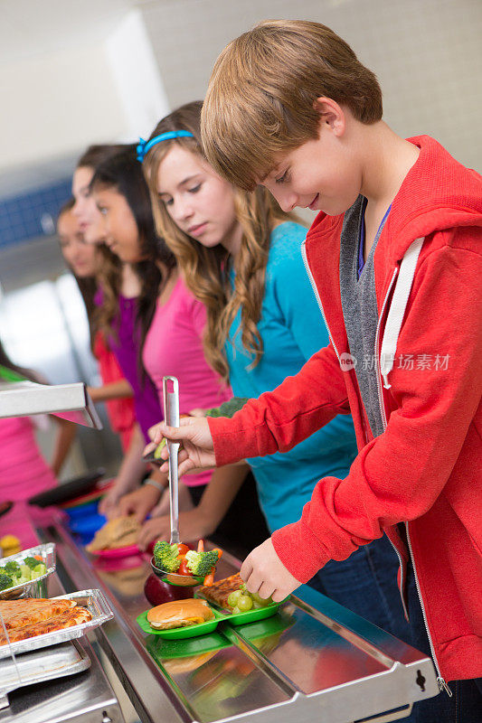快乐的中学生在自助餐厅排队买菜