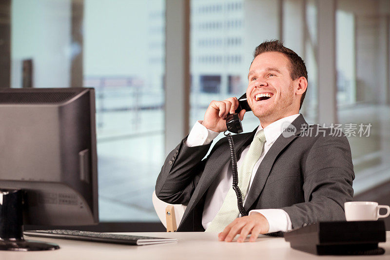 一个商人在办公室里用座机打电话