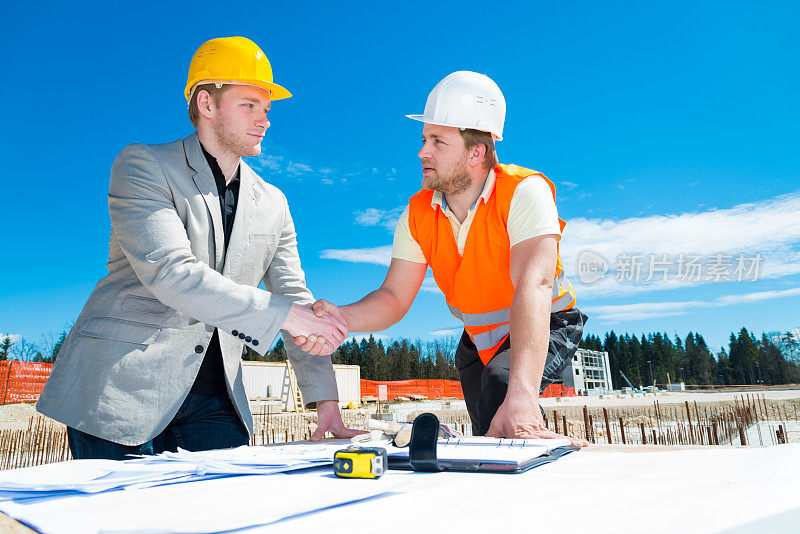 建筑师和建筑工人握手。