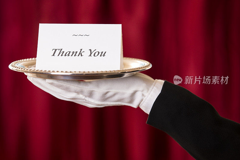 巴特勒拿着放在银盘上的“谢谢”卡片。红色的窗帘。