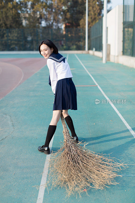 可爱的中国女大学生在操场上打扫卫生