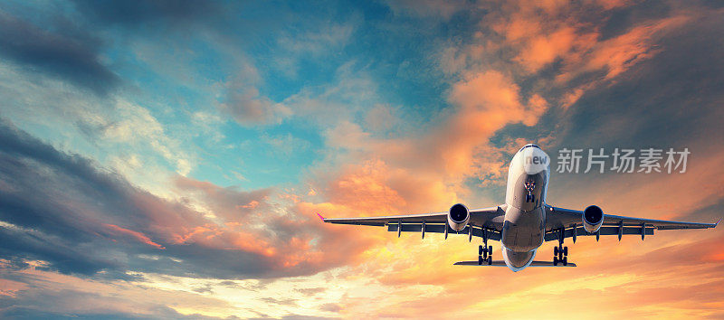 飞机着陆。日落时分，一架白色的客机在白云密布的蓝天上飞翔。旅游的背景。客运班机。商务旅行。商用飞机