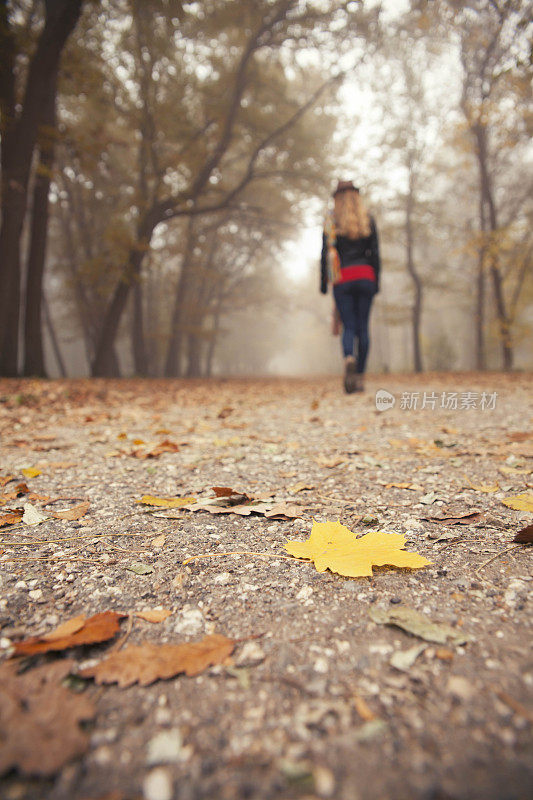 一个年轻女子在雾蒙蒙的公园里散步