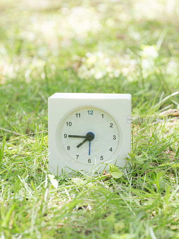 草坪上的白色简单时钟，7:45七点四十五分