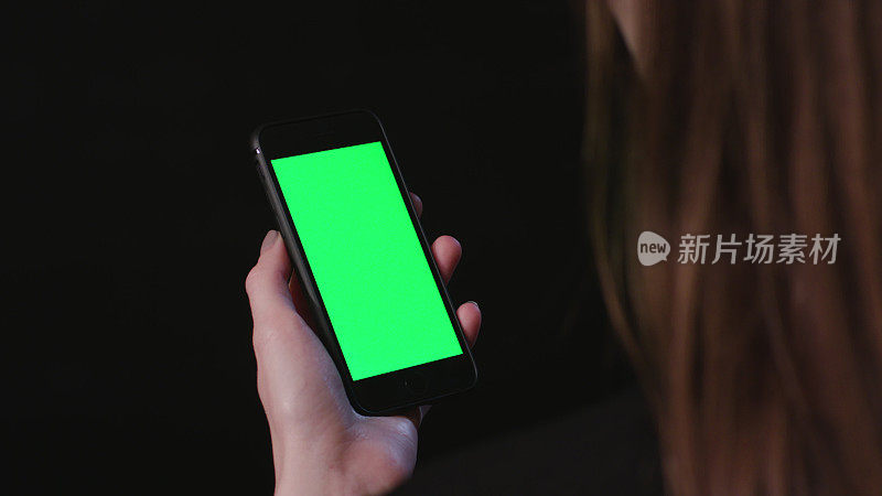 女人拿着绿色屏幕滚动的手机