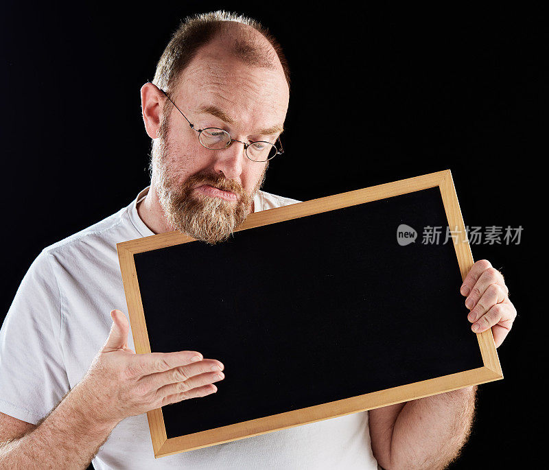 一个成熟的男人拿着空白的黑板，低头看着黑板，做着手势