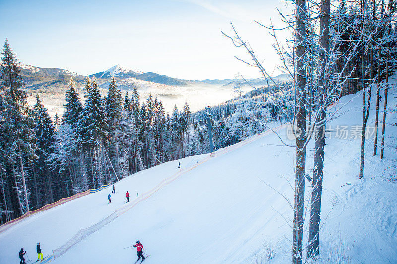 滑雪缆车上的滑雪者乘坐在滑雪胜地的美丽背景，白雪覆盖的斜坡，森林，山在乌克兰的布科威尔